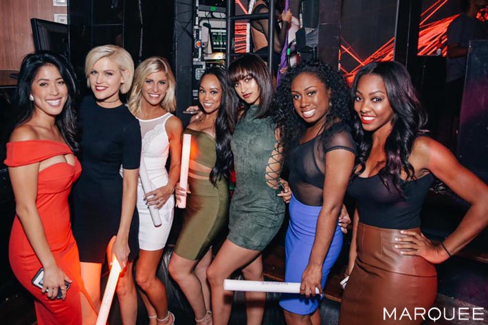 A group of attractive ladies posing in dresses and skirts.