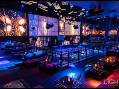 A photo of Light Nightclub's main room showing the bottle service tables and LED screens.
