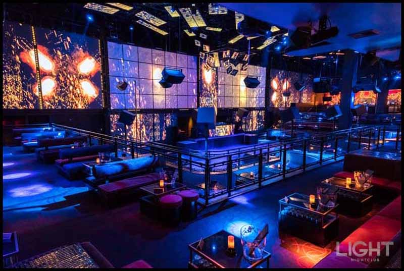 A photo of Light Nightclub's main room showing the bottle service tables and LED screens.