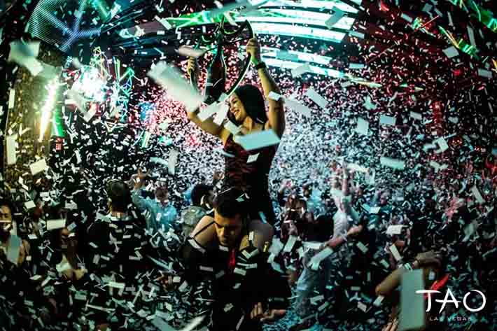 A waitress carries champagne while confetti rains down during a bottle service presentation