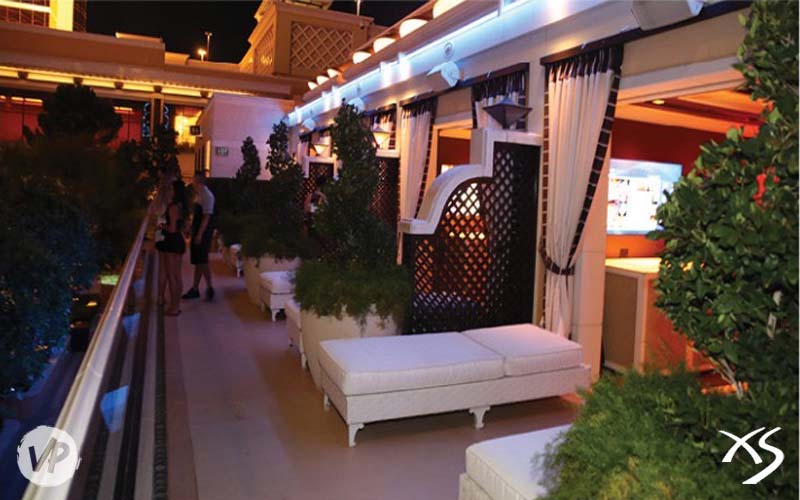 A photo showing the upper cabanas with daybeds on the second level of XS's outside section