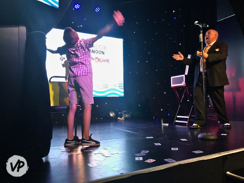 A child on stage with Adam doing the pick a card any card trick