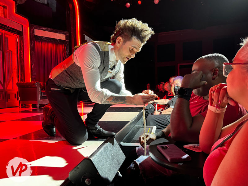 A gentlemen in the audience tests a fish hook for an illusion